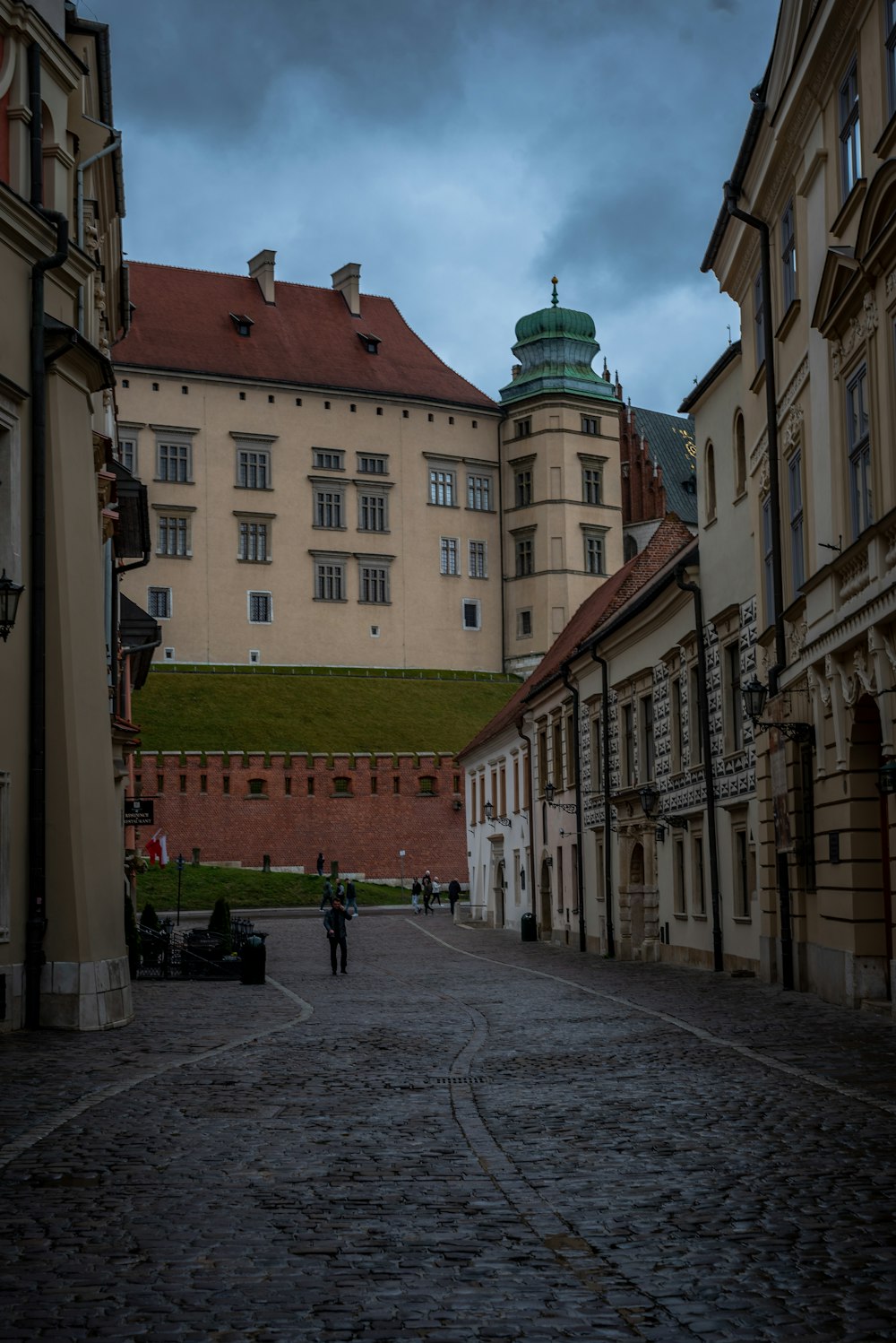 a couple of people walking down a cobblestone street