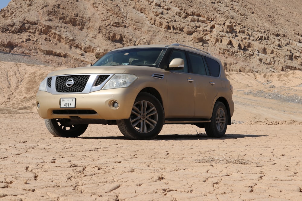 a gold nissan suv is parked in the desert