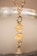 A gold pendant with an engraving is attached to a gold chain, reflecting on a mirror surface. The pendant has a circular and a hexagonal section, with delicate engraving. The reflection adds depth to the image.