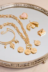 a silver tray topped with lots of gold jewelry