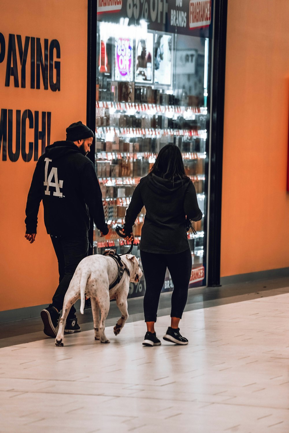 a man and a woman walking a dog in front of a store