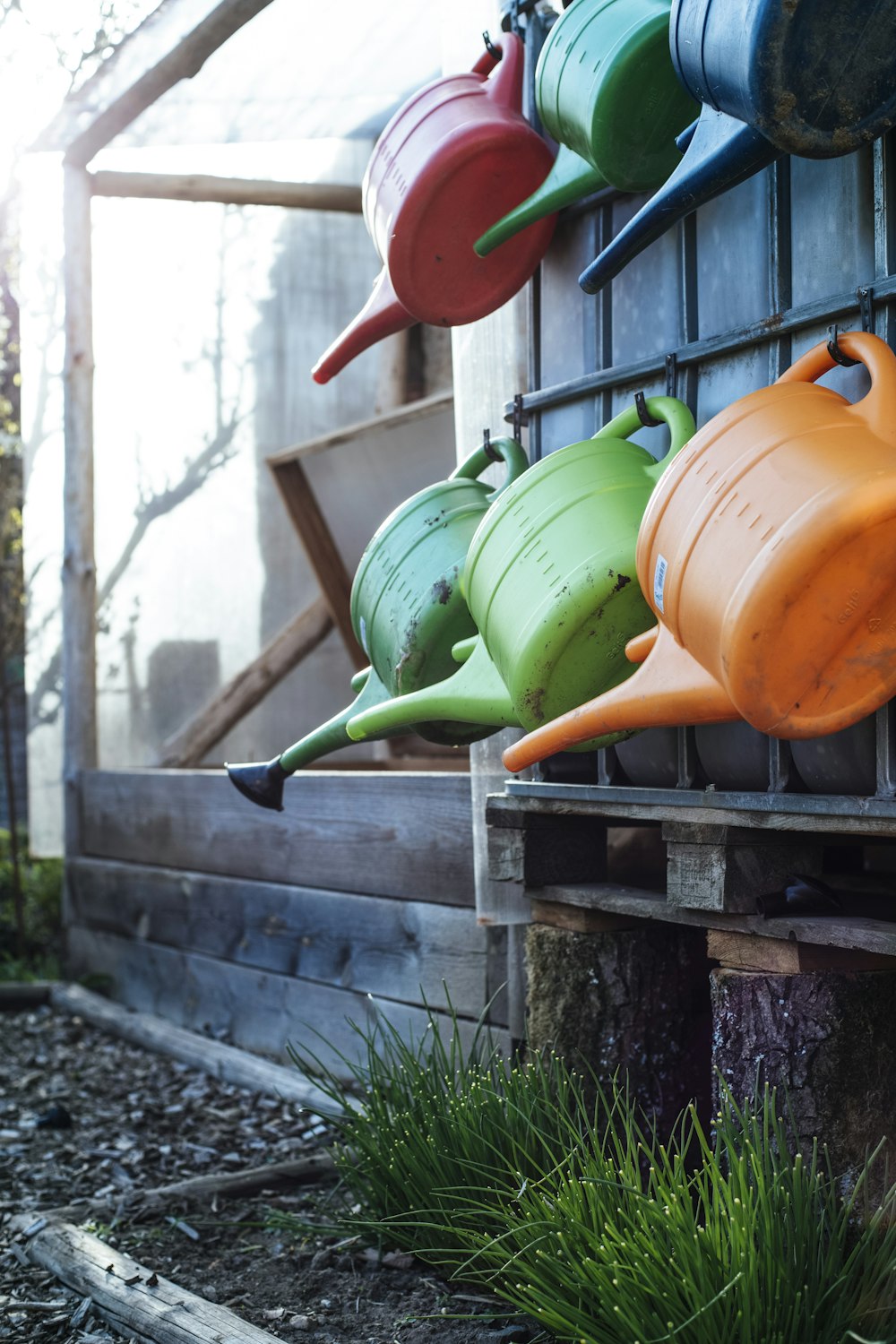 a row of colorful watering cans hanging from a wall
