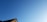 A section of a roof is visible in the lower part of the image against a clear blue sky. The roof is composed of tiles with a reddish-brown hue, partially illuminated by sunlight.