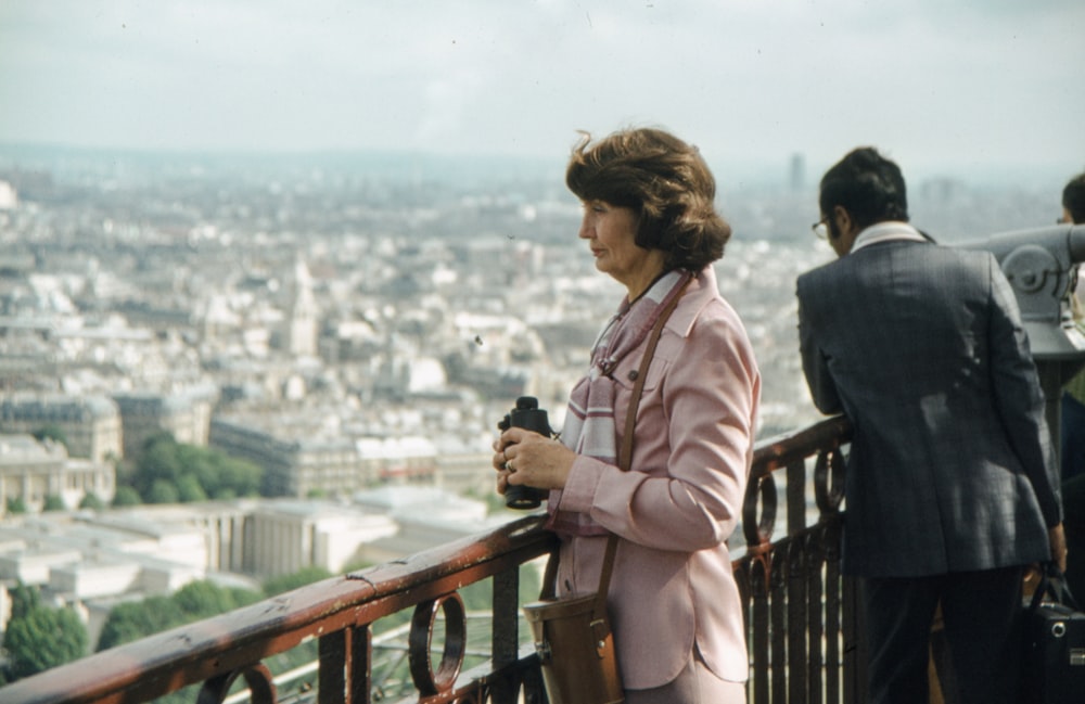 a woman in a pink suit standing on a balcony