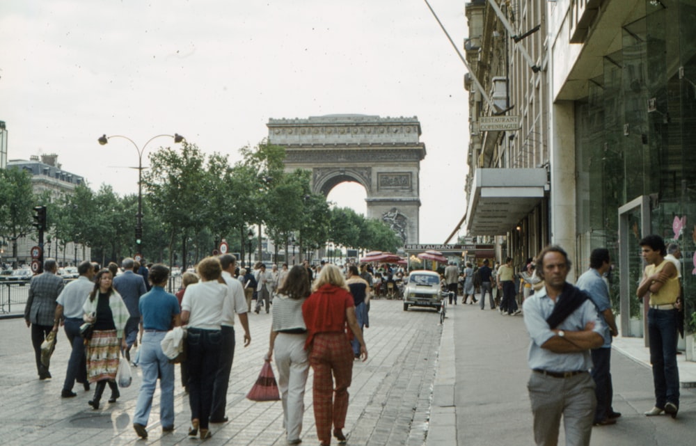 a group of people walking down a street next to a tall building