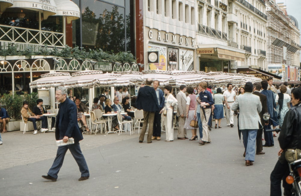 a crowd of people walking down a street next to tall buildings