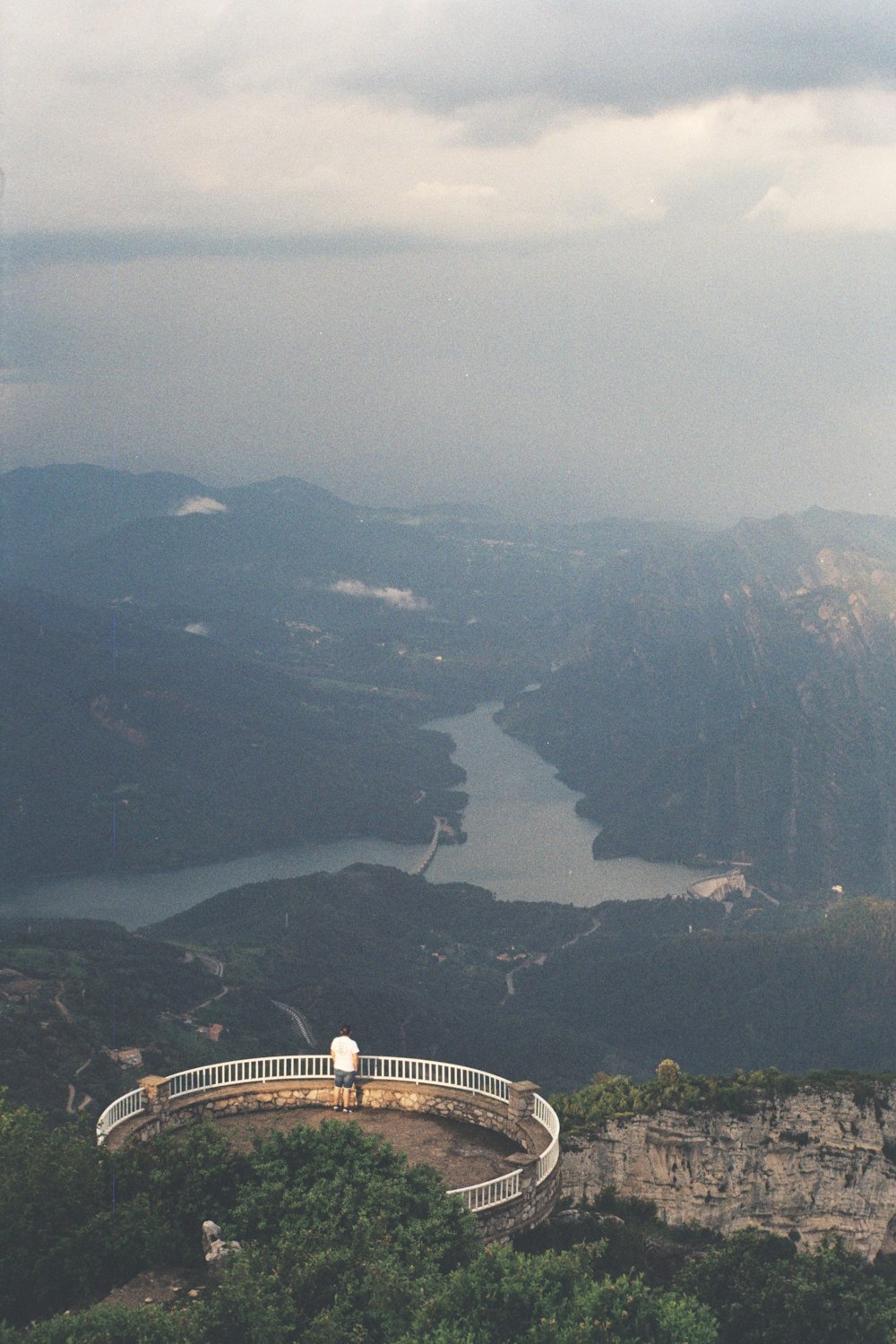 a man standing on top of a mountain overlooking a lake