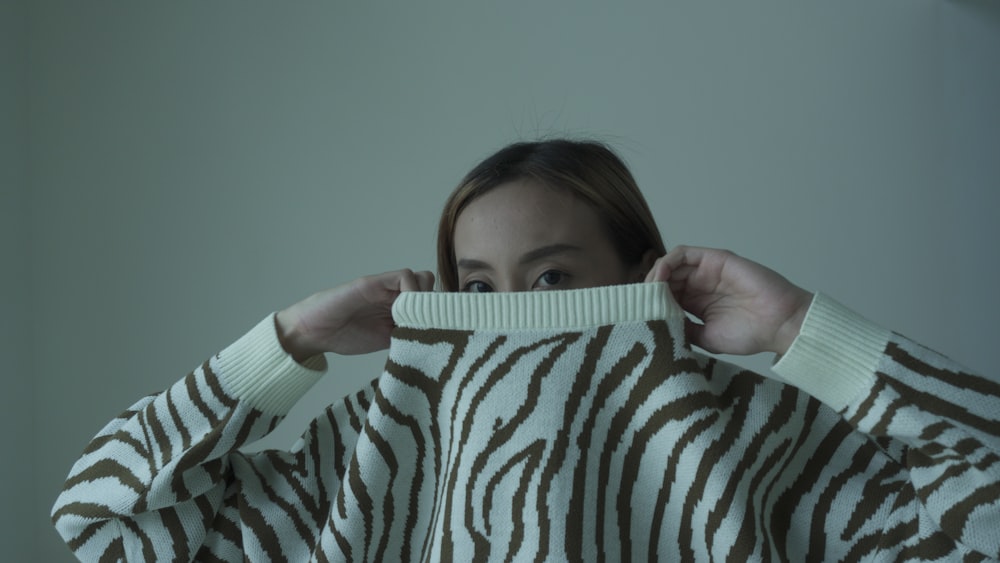 a woman holding a sweater over her face