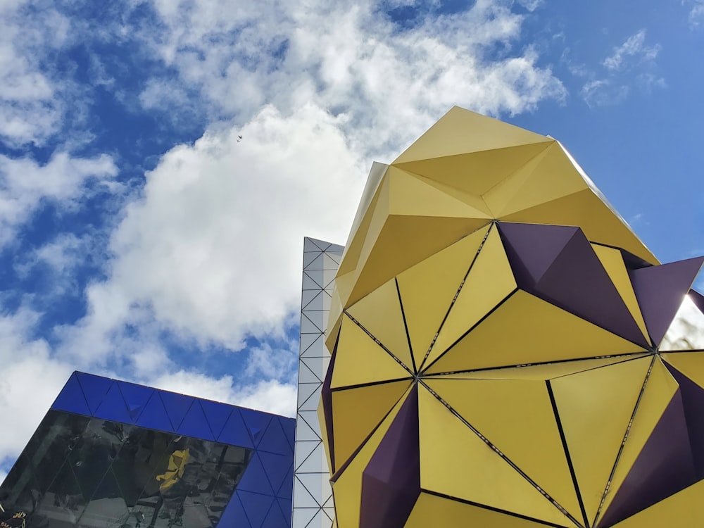 um grande guarda-chuva amarelo sentado ao lado de um edifício azul