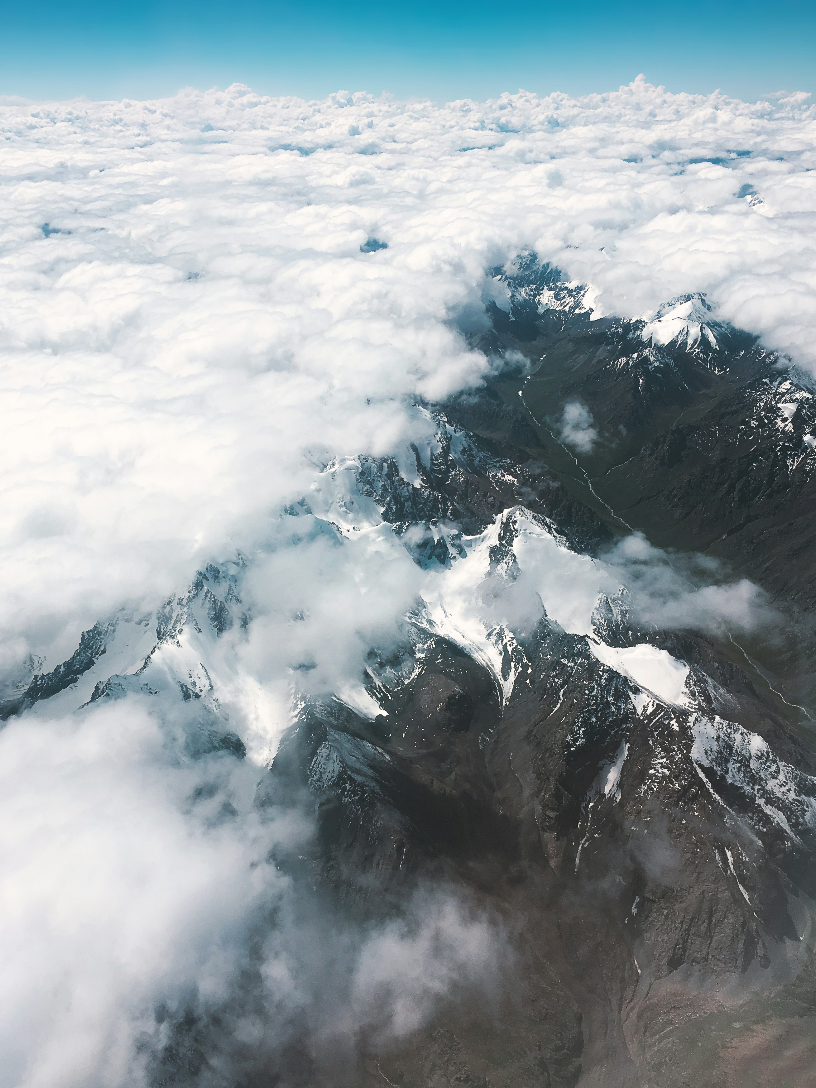 an aerial view of a mountain range covered in clouds