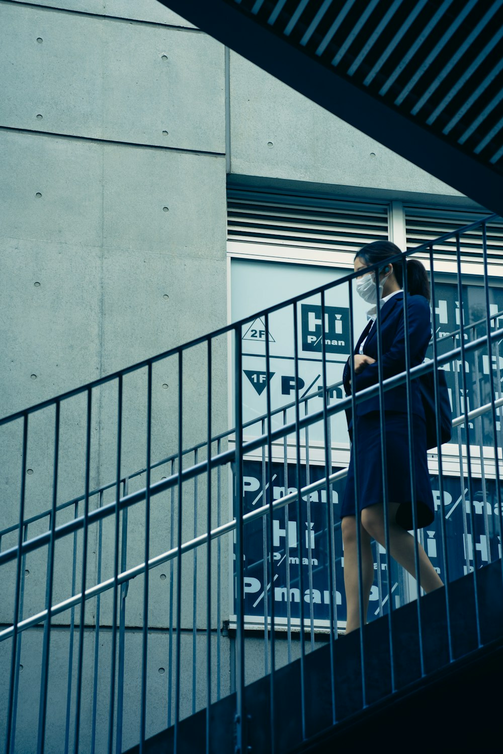 a woman wearing a face mask walking down a flight of stairs