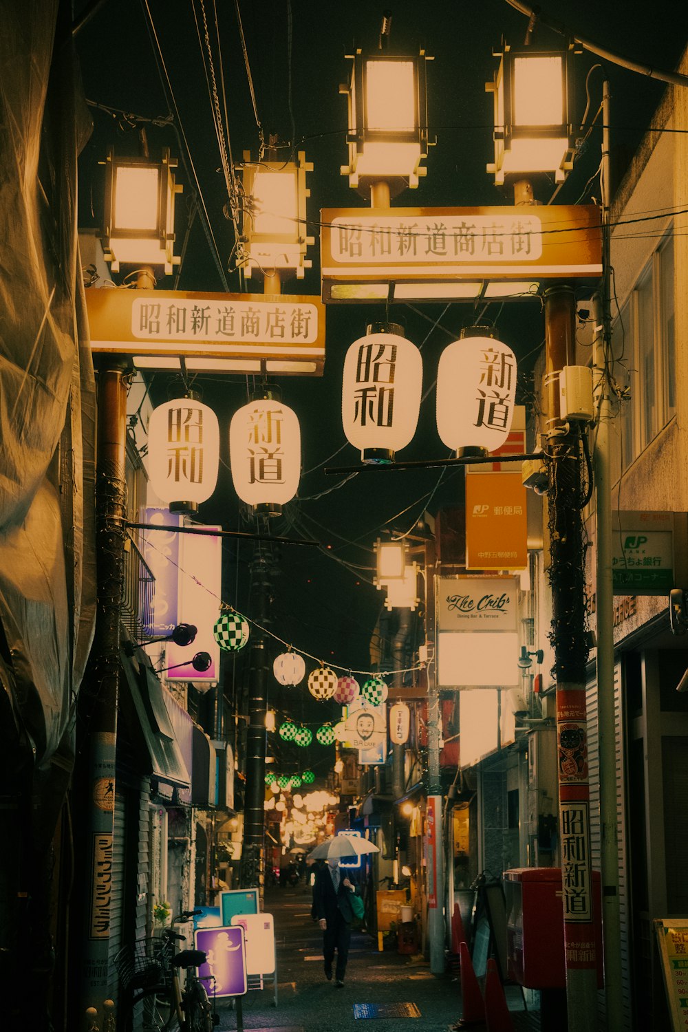 a person walking down a street under some lights