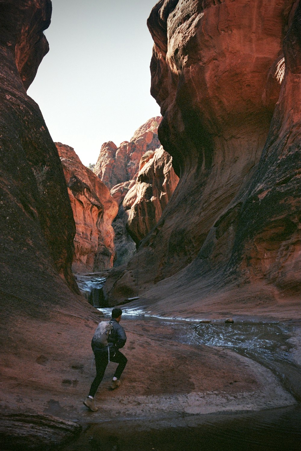 a man walking through a canyon next to a river
