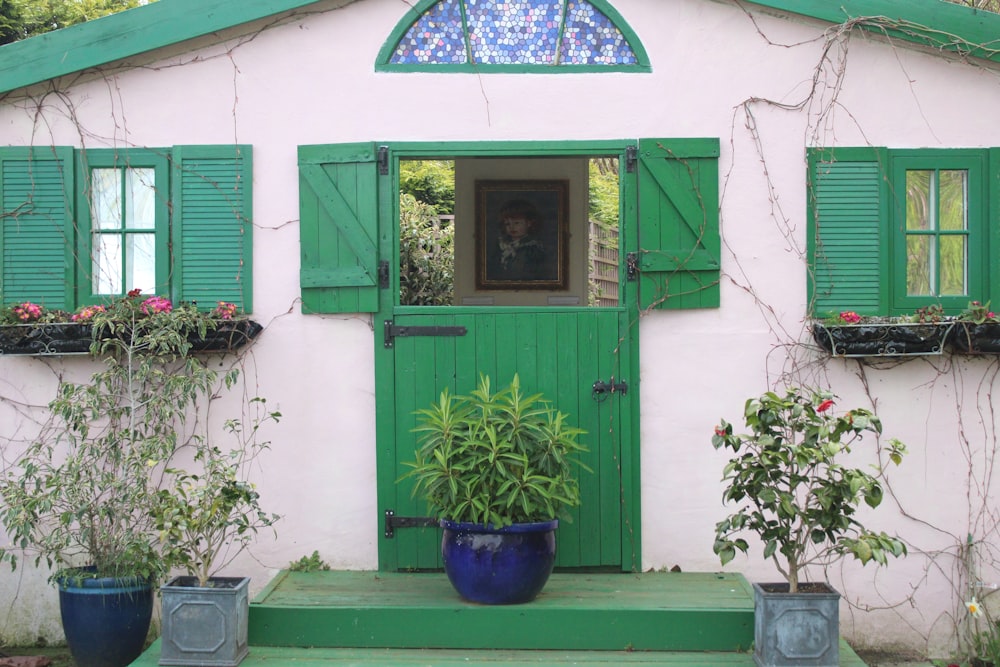 a pink house with green shutters and potted plants