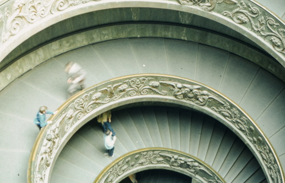 two people walking up a spiral staircase in a building