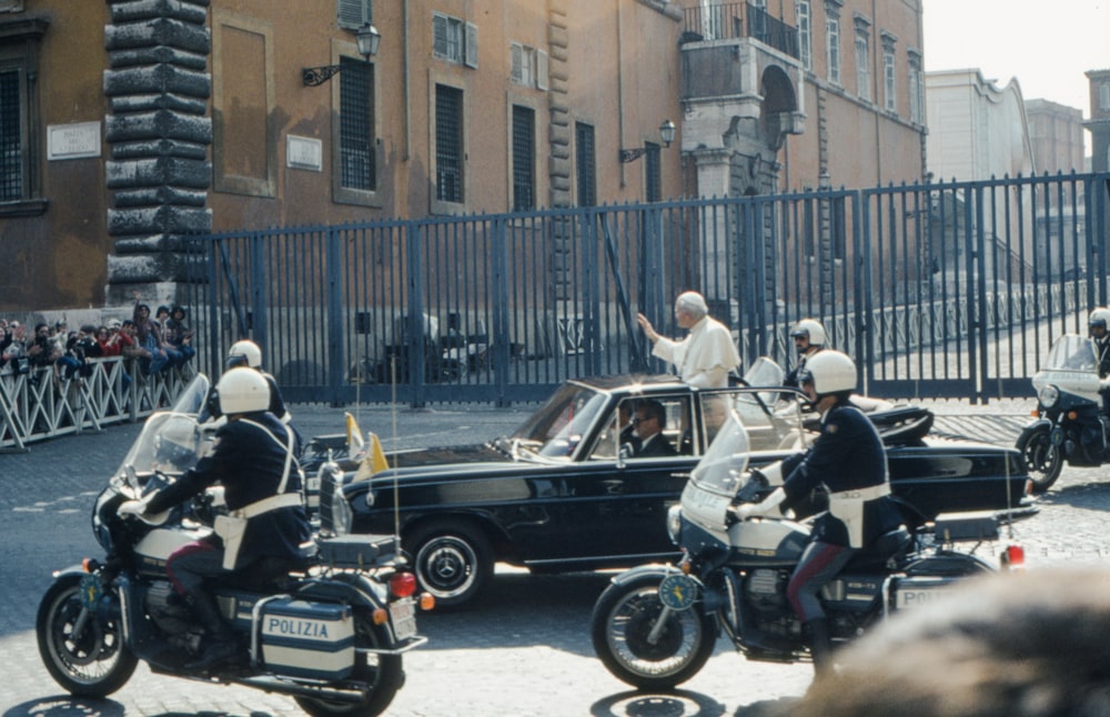 a group of men riding motorcycles next to a car