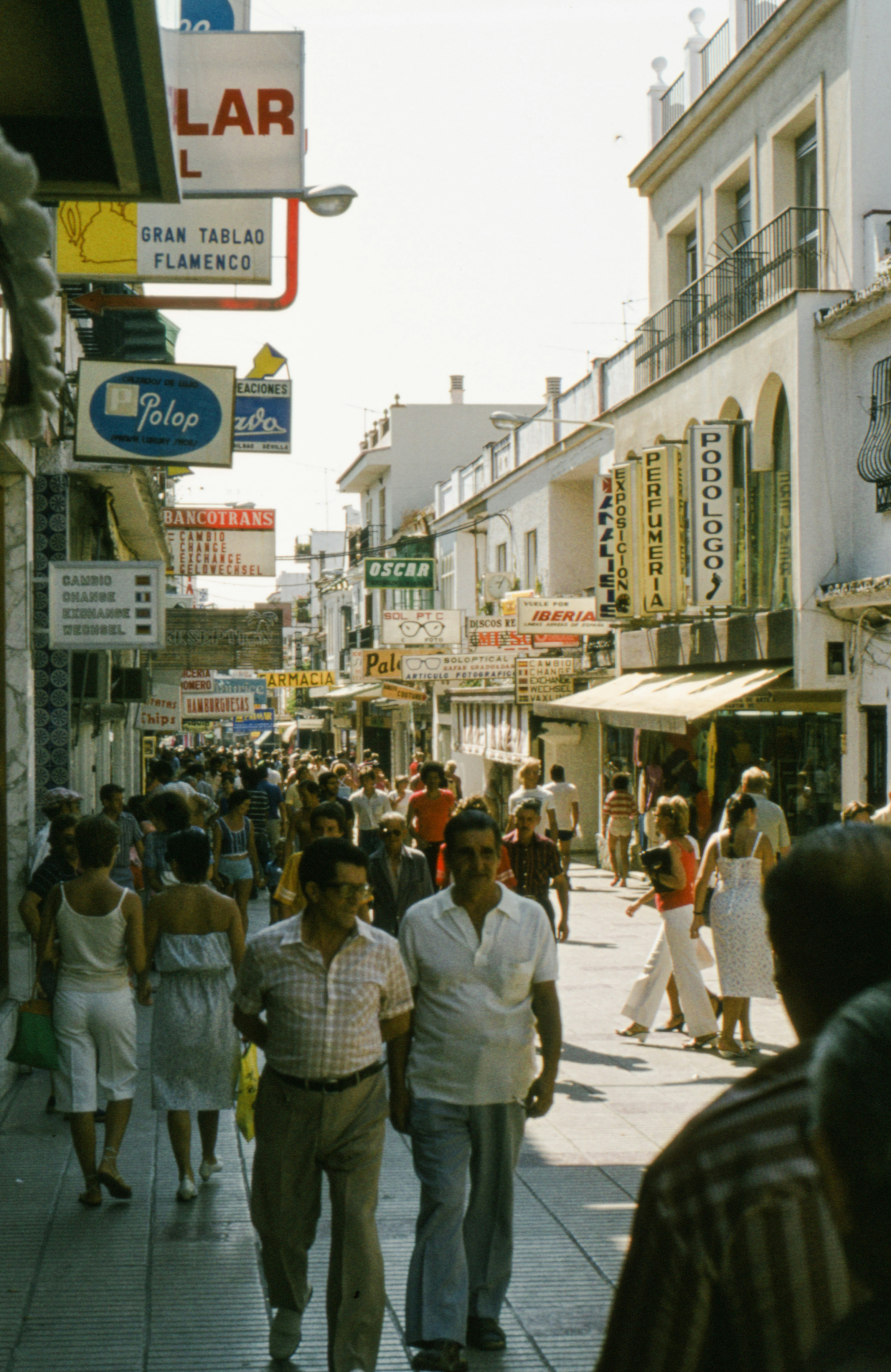 a crowd of people walking down a street next to tall buildings