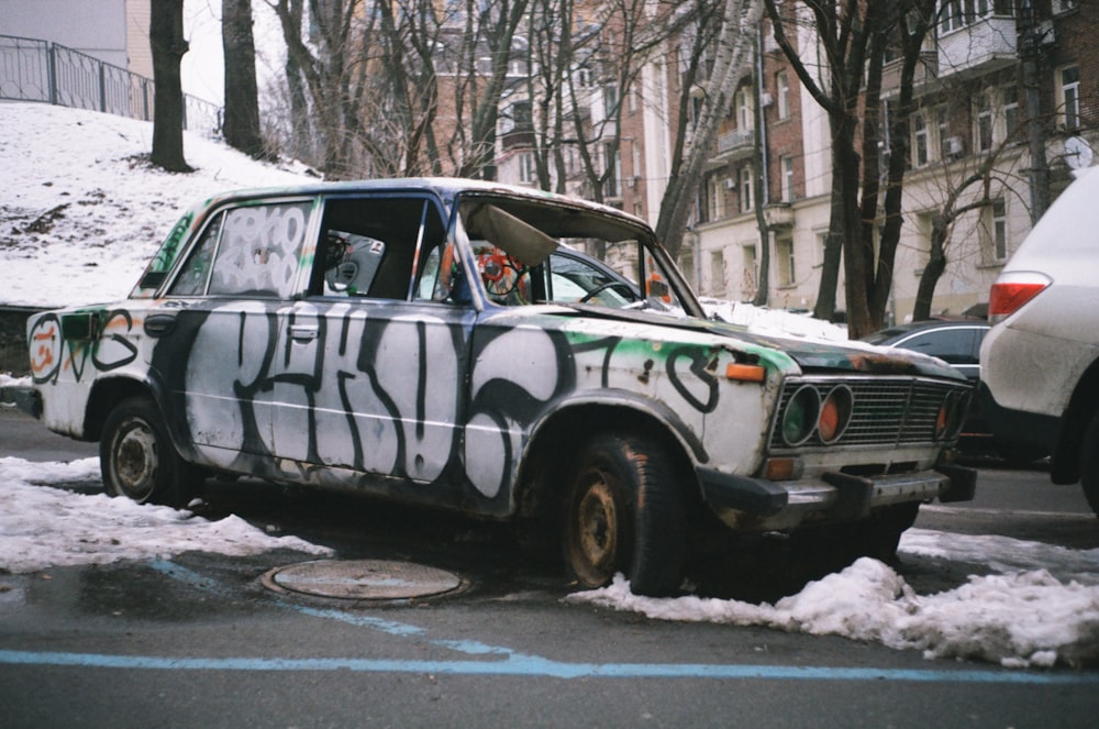 a car covered in graffiti parked on the side of the road