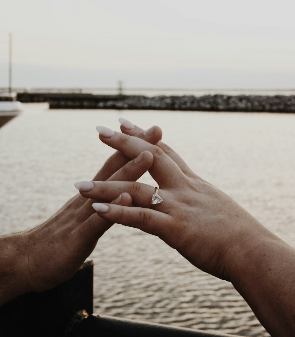 two people holding hands over a body of water