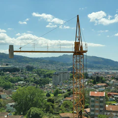 A dramatic full-screen video still of a construction crane moving smoothly over a cityscape.