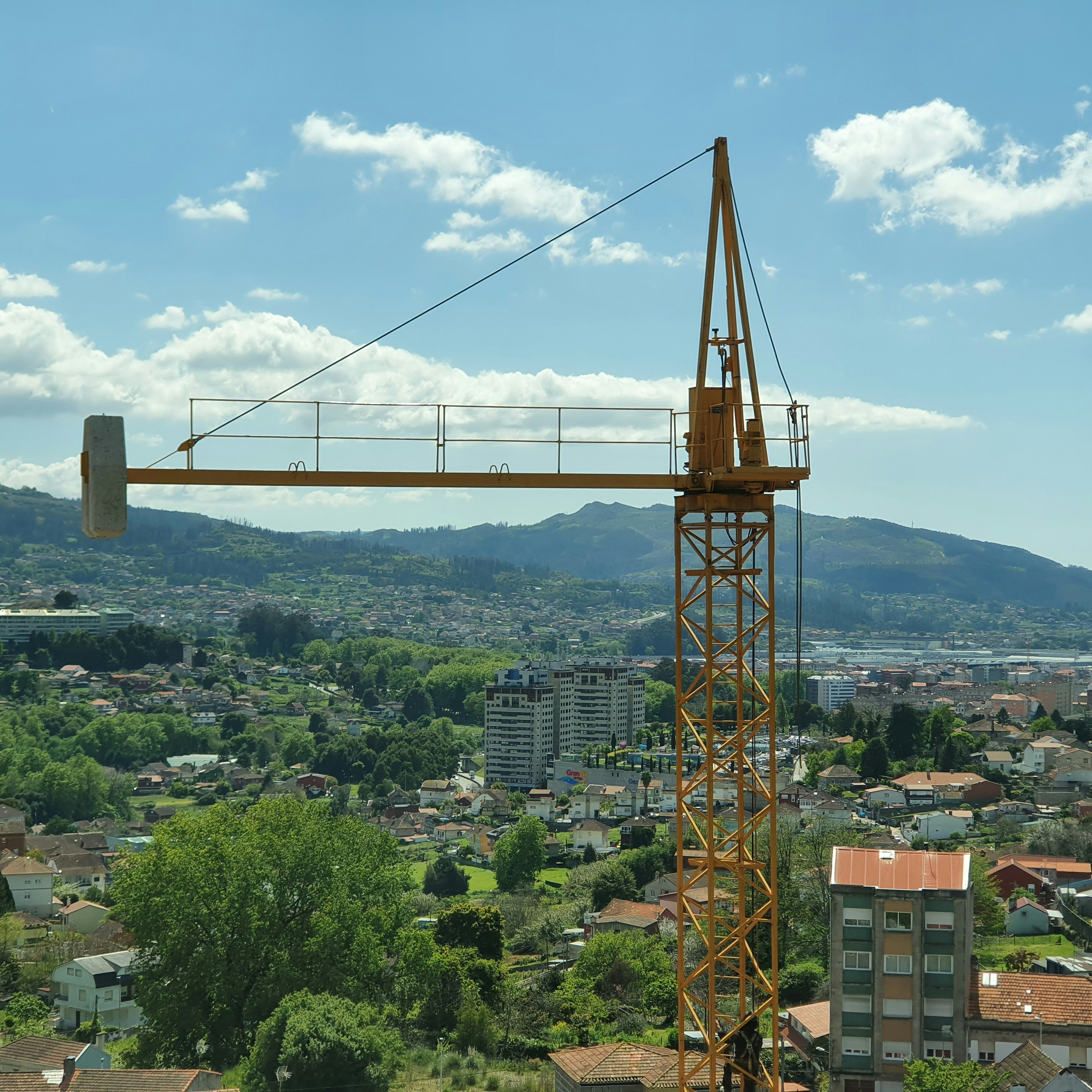 A crane during assembly with a nice mixed nature & city landscape in the background