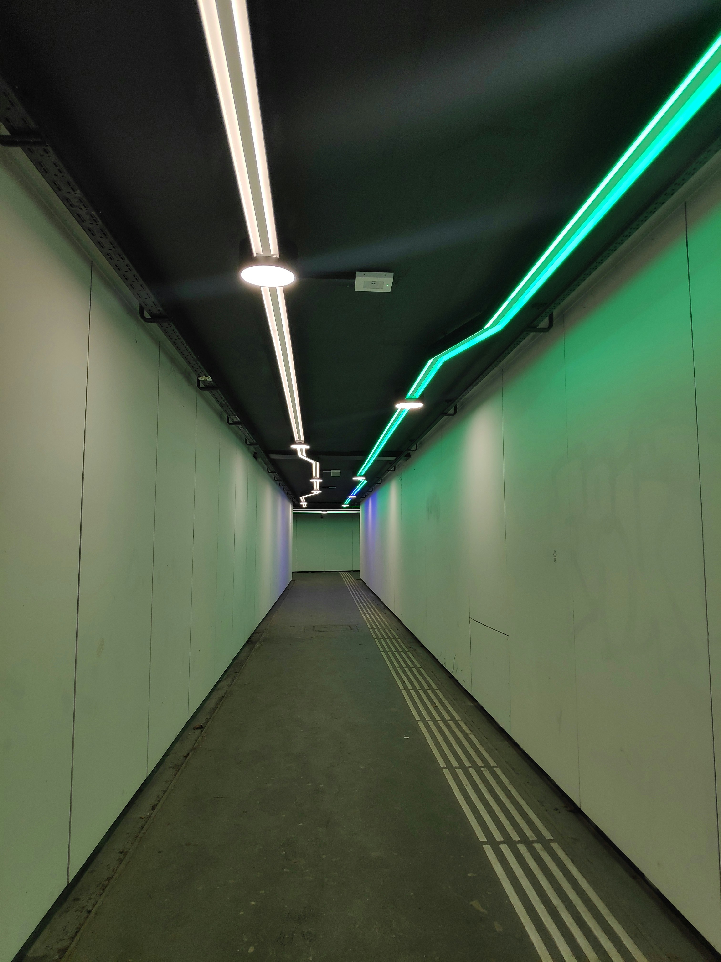 a long hallway with green and white lights