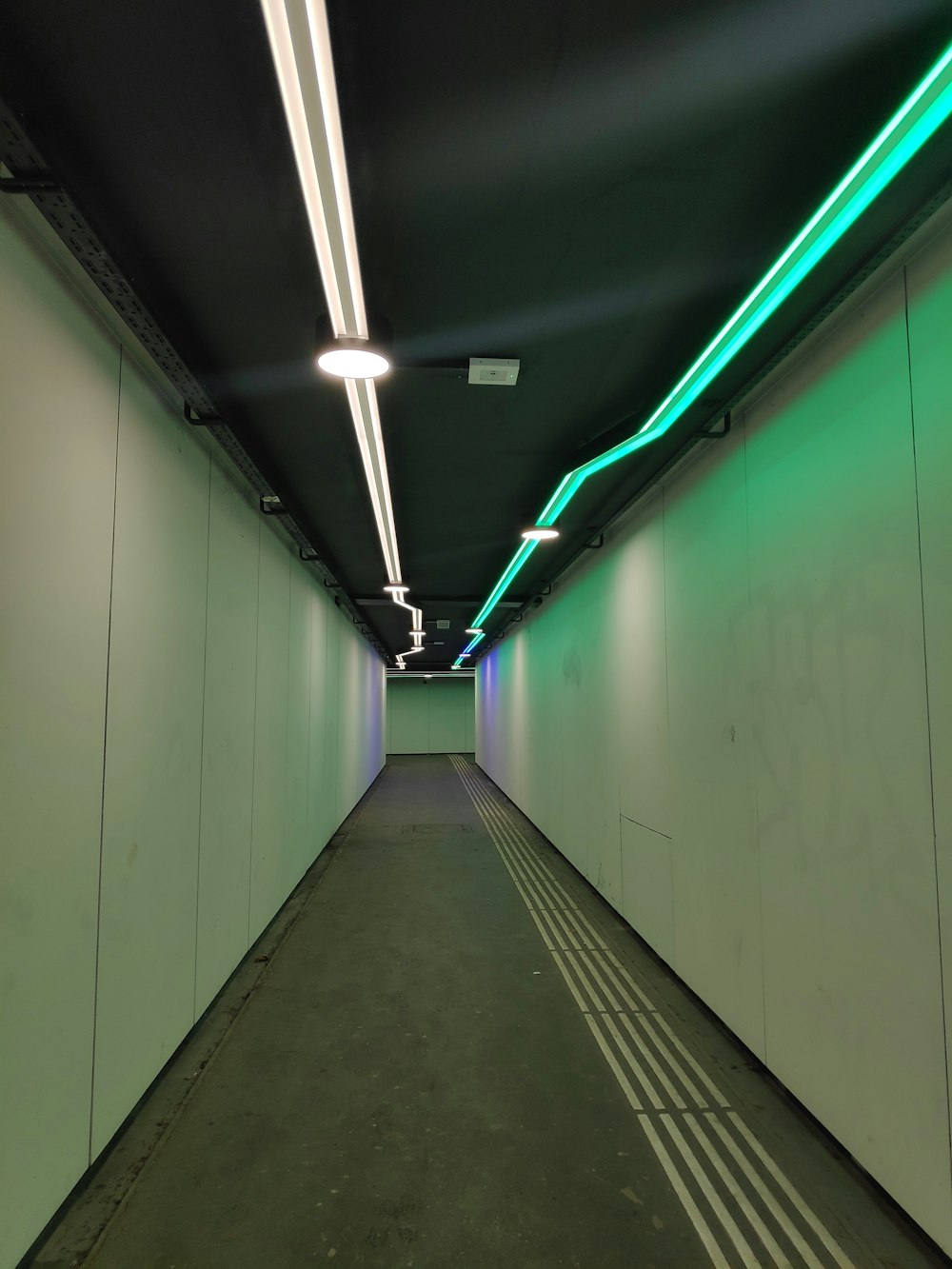 a long hallway with green and white lights