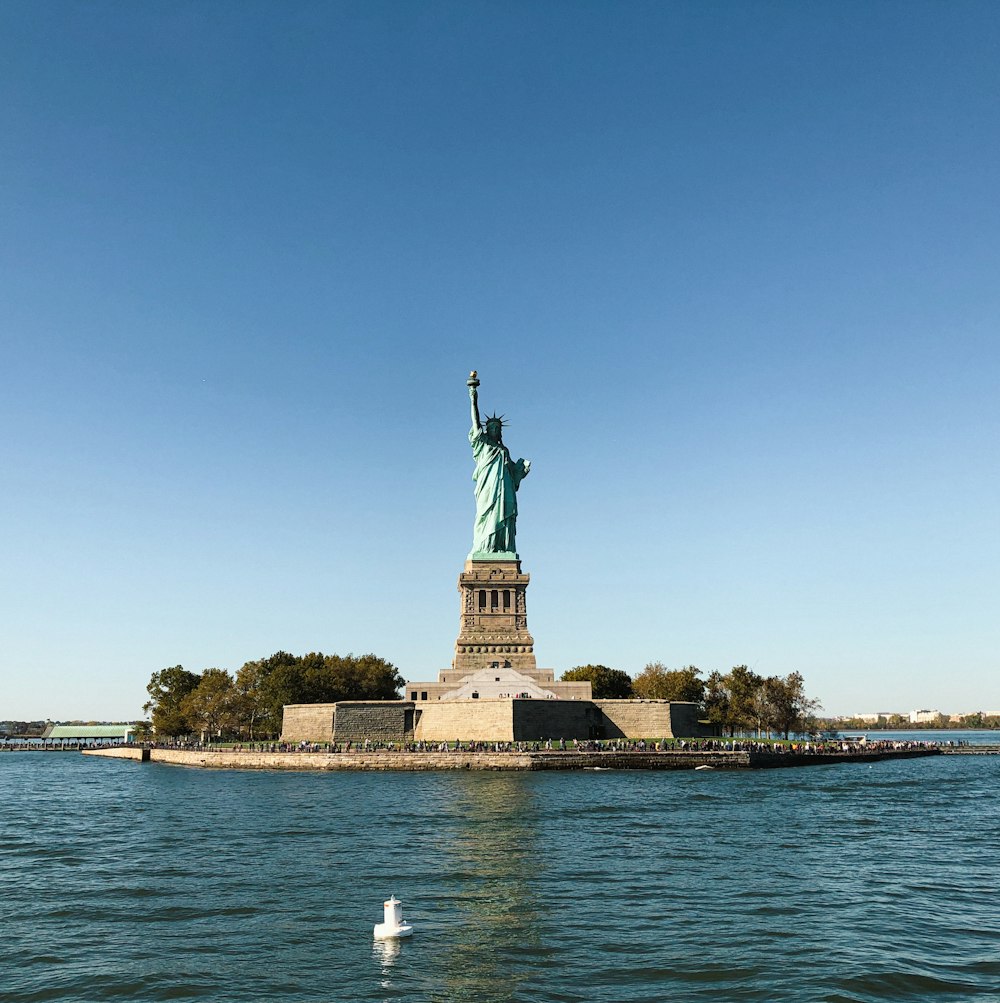 the statue of liberty stands in the middle of the water