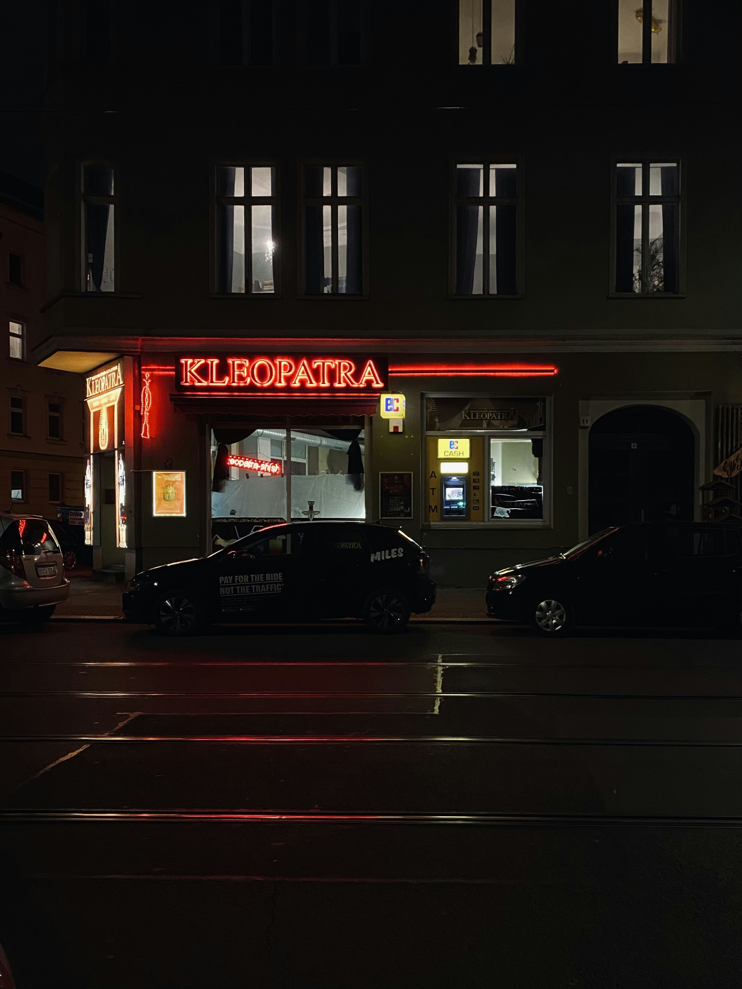a dark city street at night with cars parked on the side of the street
