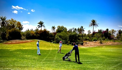 Golf pro leading a group through a sunlit fairway surrounded by tropical foliage.