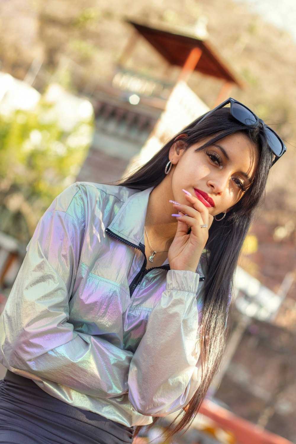 a woman in a silver jacket and sunglasses posing for a picture