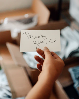 a hand holding a note that says thank you