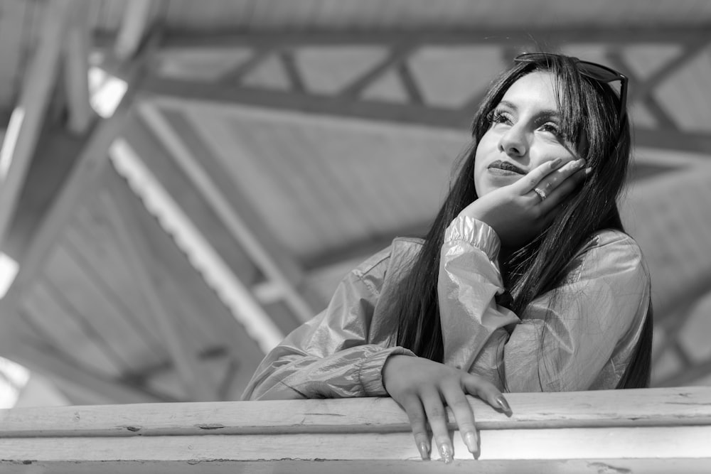 a black and white photo of a woman leaning on a rail