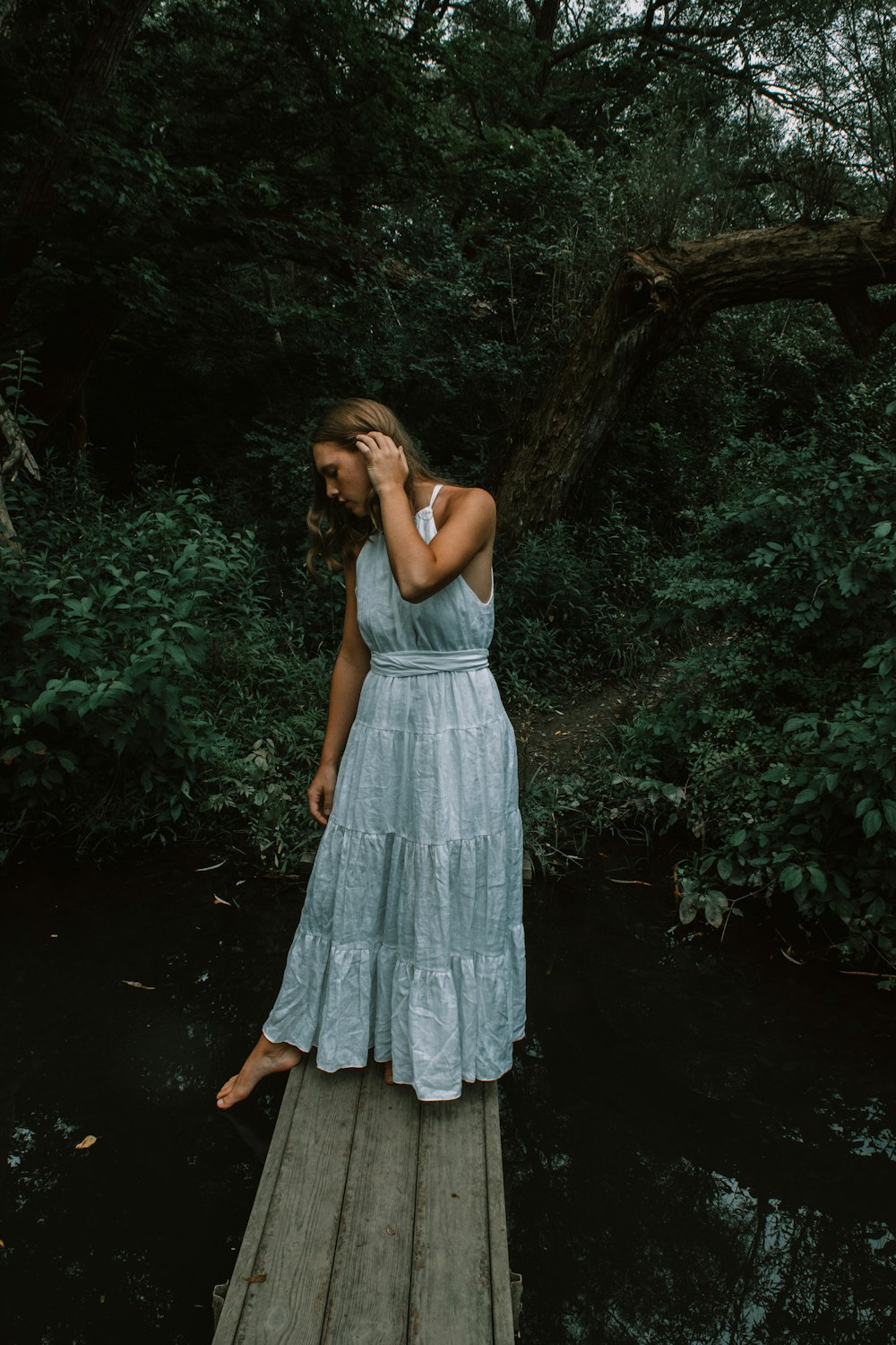 a woman in a blue dress standing on a dock