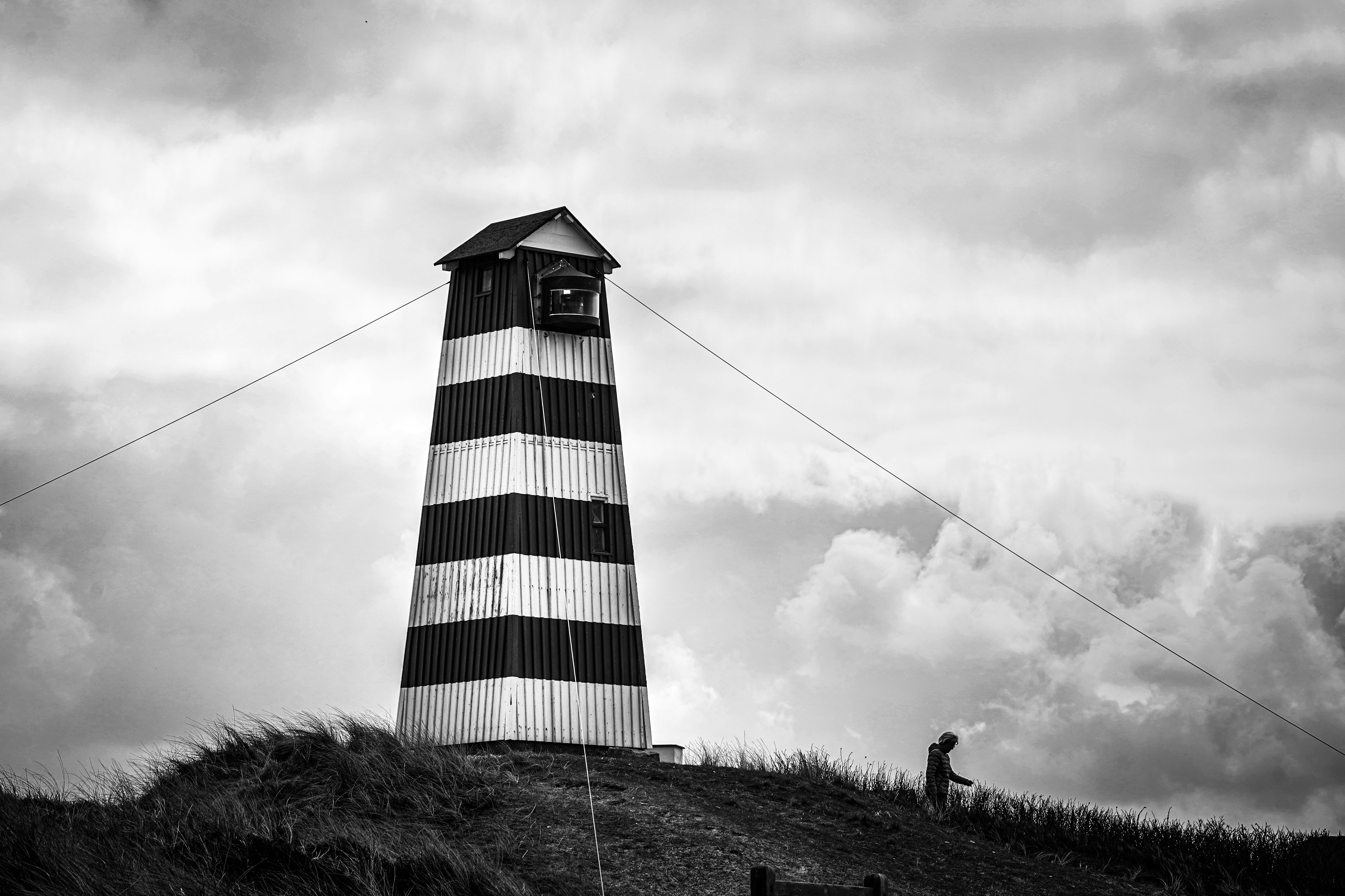a black and white photo of a lighthouse on a hill