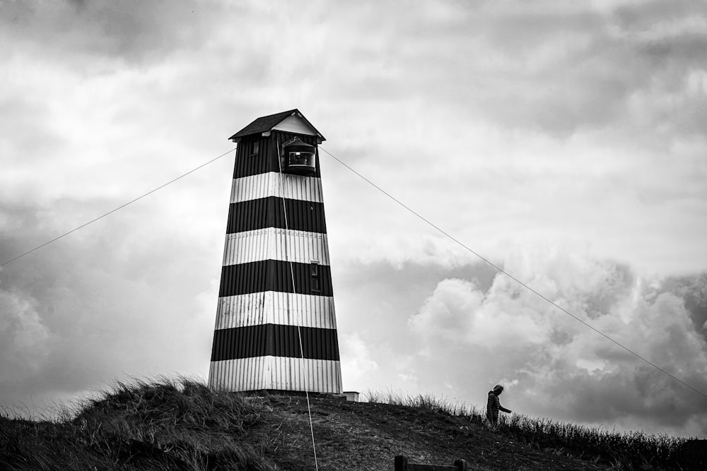 a black and white photo of a lighthouse on a hill