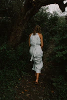 A serene scene of a model walking barefoot on a forest path wearing organic cotton clothes.