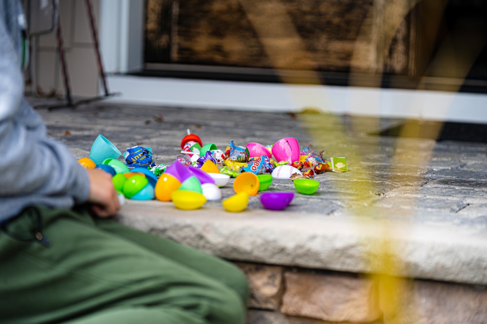 a person sitting on a step next to a pile of toys