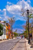 a city street with a lamp post and a mountain in the background