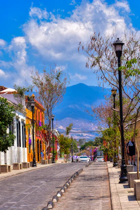 a city street with a lamp post and a mountain in the background