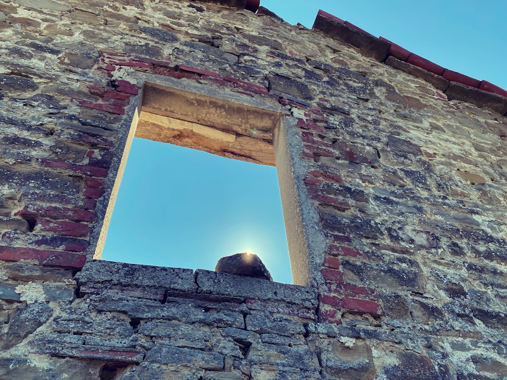a window in a brick wall with a blue sky in the background