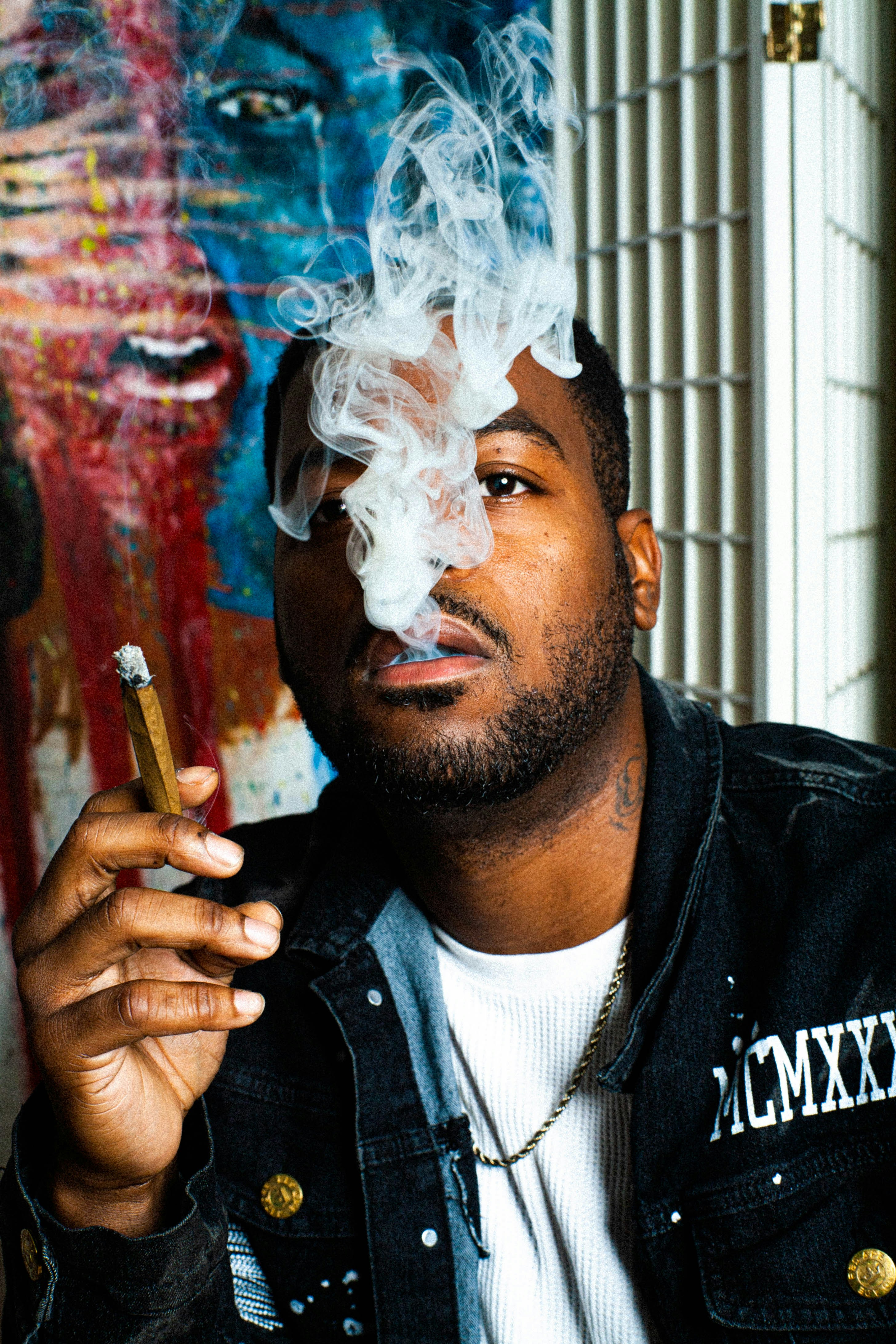 a man smoking a cigarette in front of a painting