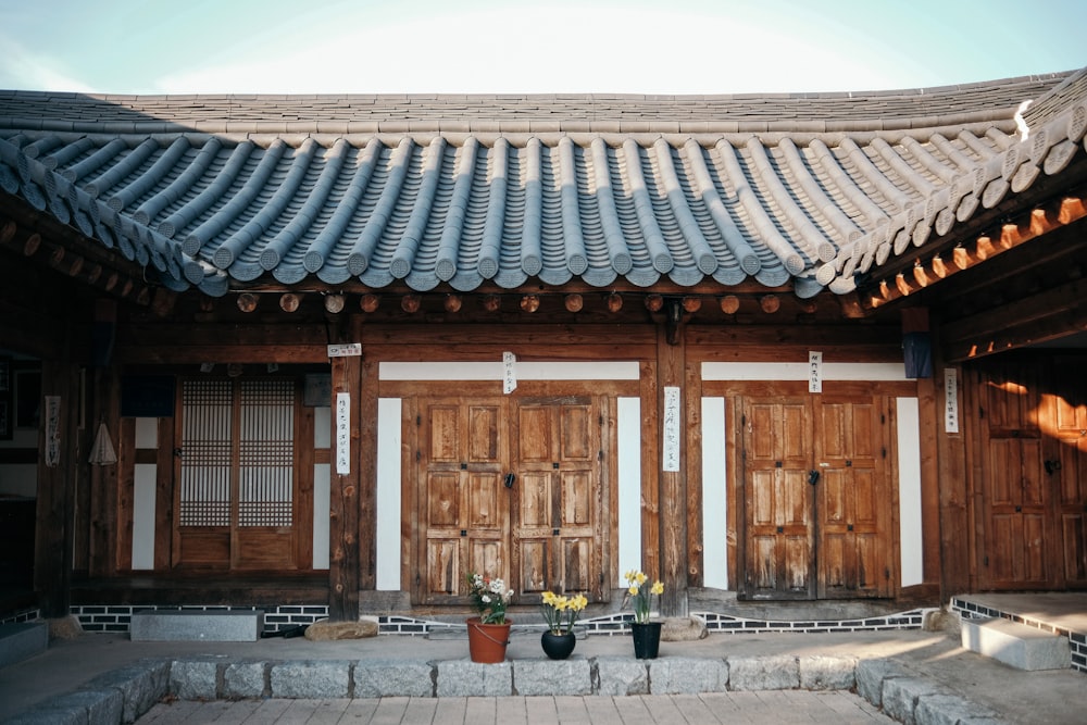 a wooden building with two potted plants in front of it