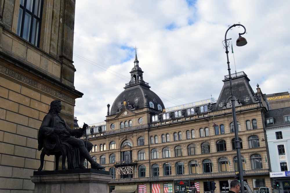 a statue of a man sitting on a bench in front of a building