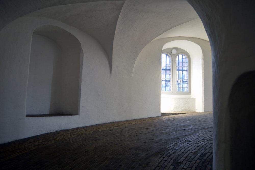 a room with arched windows and a brick floor