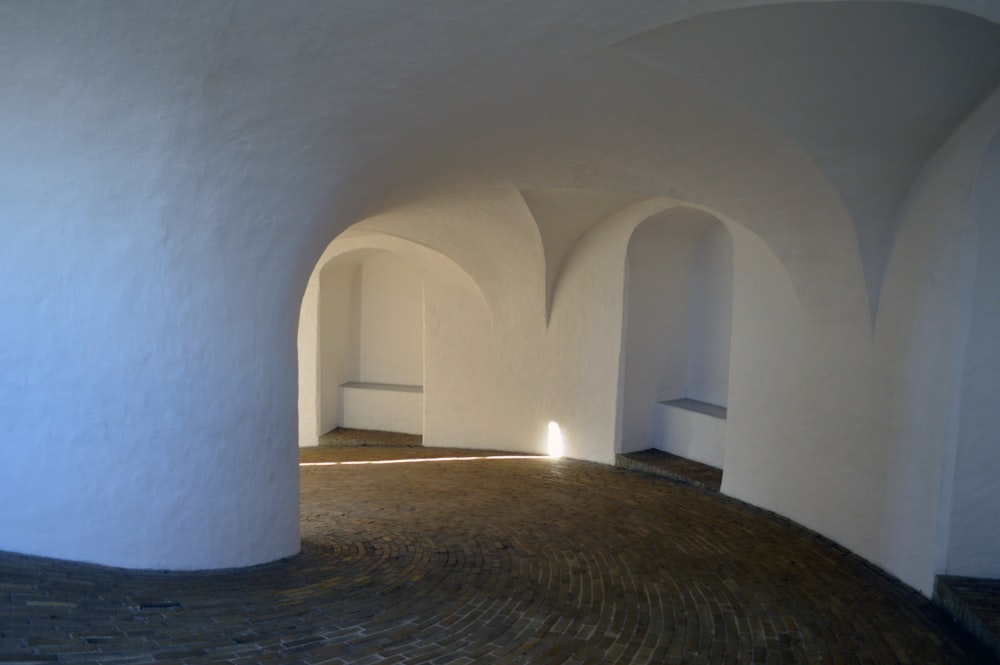 an empty room with a brick floor and white walls