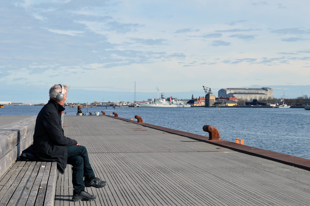 a man sitting on a pier looking at the water