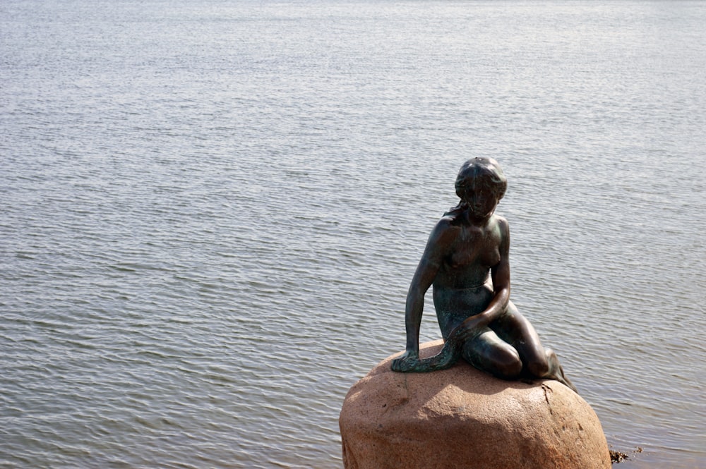 Una estatua de una mujer sentada en la cima de una roca