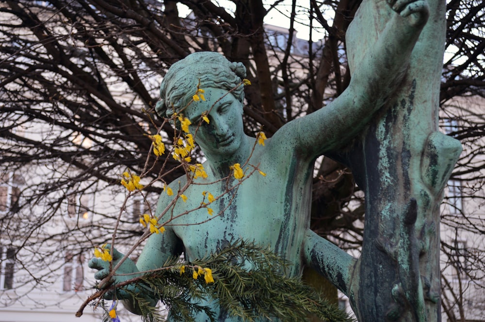 a statue of a woman holding a branch with yellow flowers
