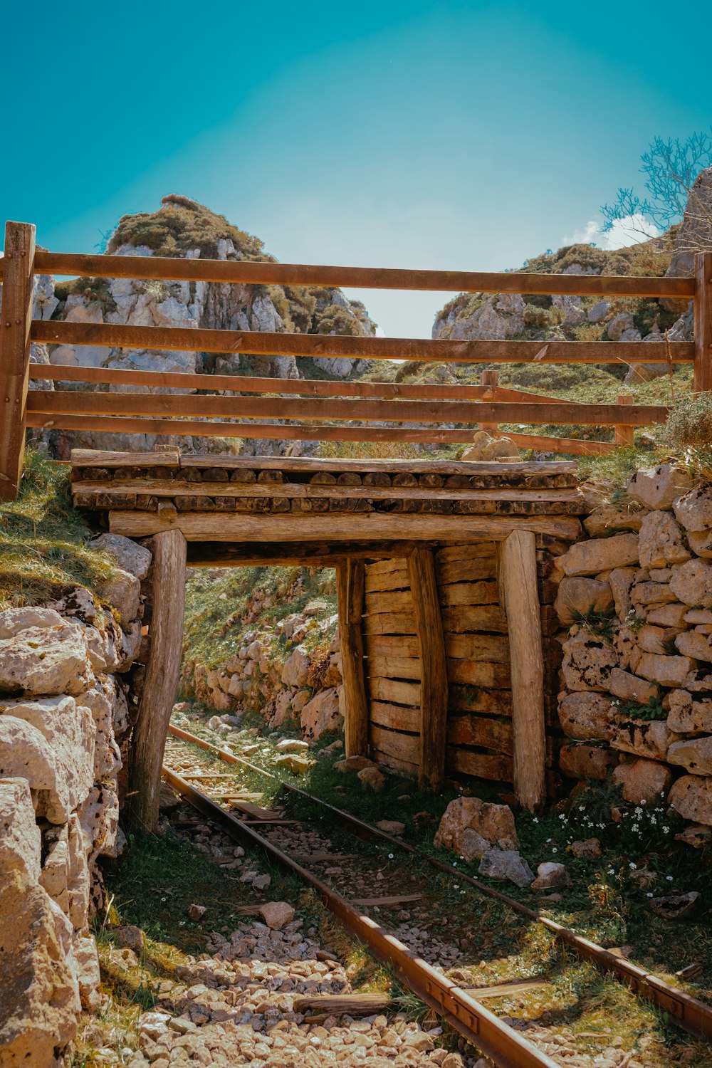 a wooden bridge over train tracks in a rocky area